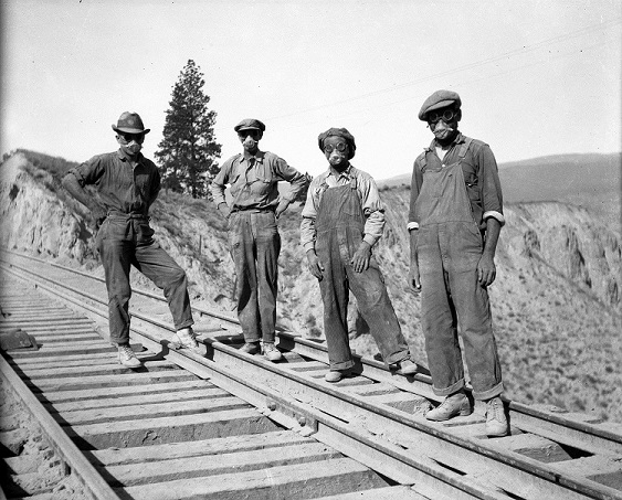 Four men in dust marks standing on a railway